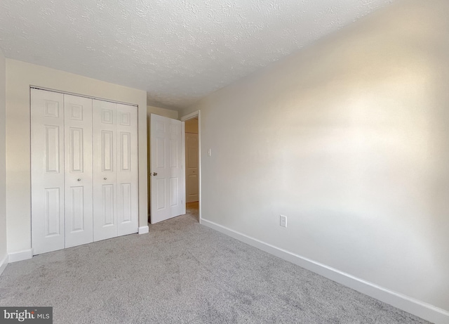 unfurnished bedroom featuring a closet, a textured ceiling, and light carpet