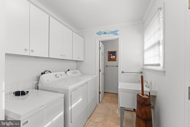 clothes washing area featuring ornamental molding, cabinet space, a sink, and washing machine and clothes dryer