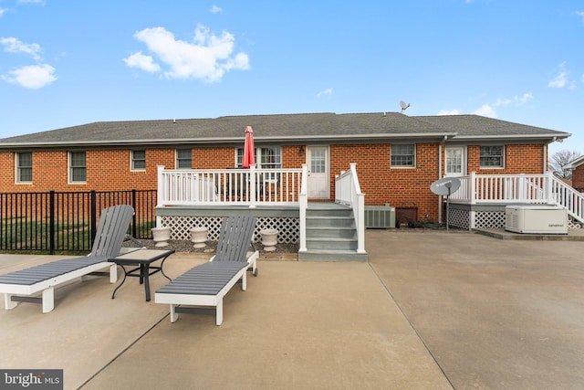 back of property featuring cooling unit, a patio area, brick siding, and a wooden deck