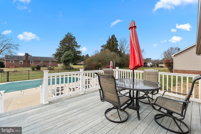 deck with a yard, outdoor dining area, fence, and a fenced in pool