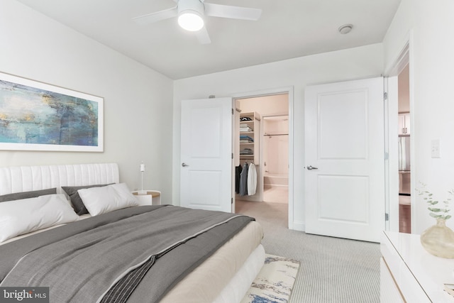 carpeted bedroom with a walk in closet and ceiling fan