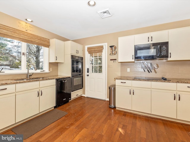 kitchen featuring light stone countertops, sink, black appliances, hardwood / wood-style floors, and white cabinetry