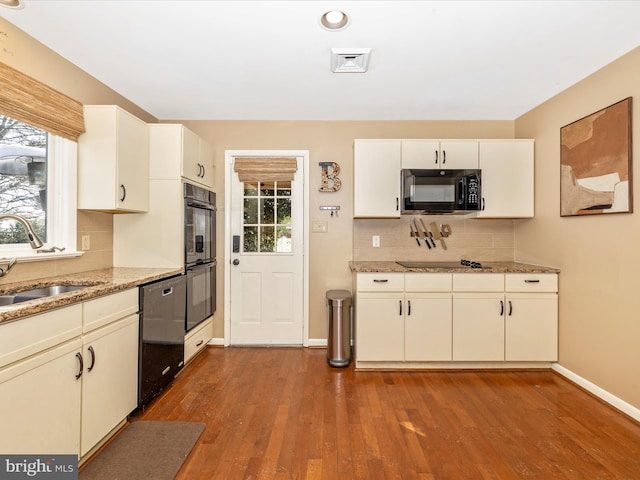 kitchen featuring black appliances, sink, hardwood / wood-style flooring, tasteful backsplash, and light stone counters