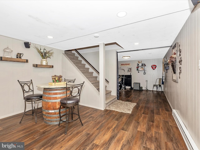 dining space with dark hardwood / wood-style flooring, a baseboard radiator, and wooden walls