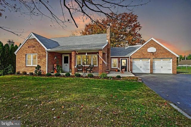 view of front of home with a yard, a porch, and a garage