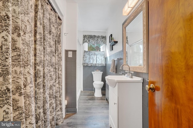 bathroom with a shower with curtain, wood-type flooring, toilet, vanity, and tile walls