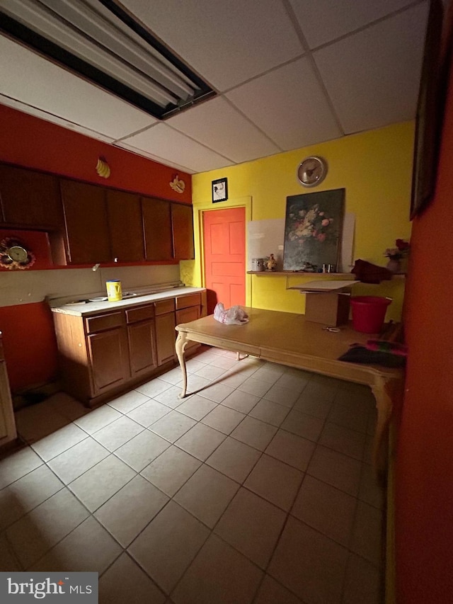 kitchen with a paneled ceiling and light tile patterned floors