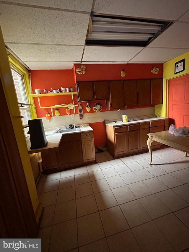 kitchen with sink, light tile patterned flooring, and a drop ceiling