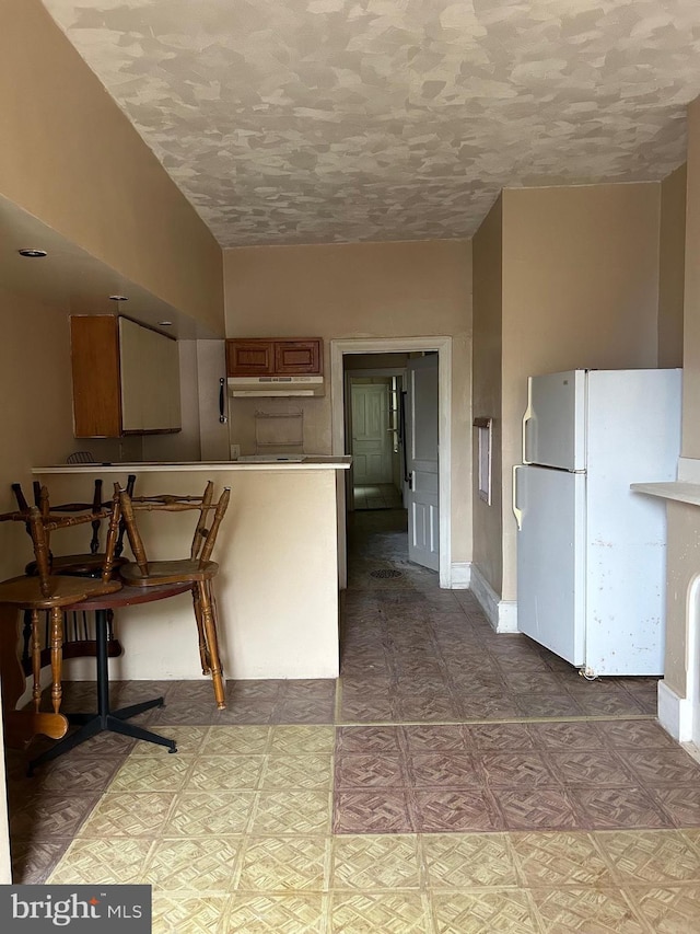 kitchen with a textured ceiling and white refrigerator