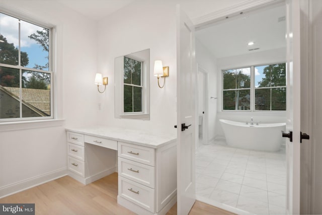 bathroom featuring a wealth of natural light, a washtub, vanity, and hardwood / wood-style floors