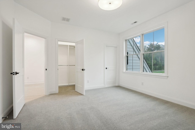 unfurnished bedroom with a closet and light colored carpet