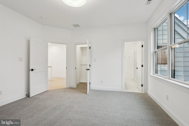 unfurnished bedroom featuring light carpet and connected bathroom