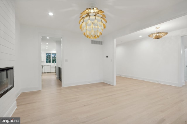 interior space with a notable chandelier, light hardwood / wood-style floors, and a fireplace