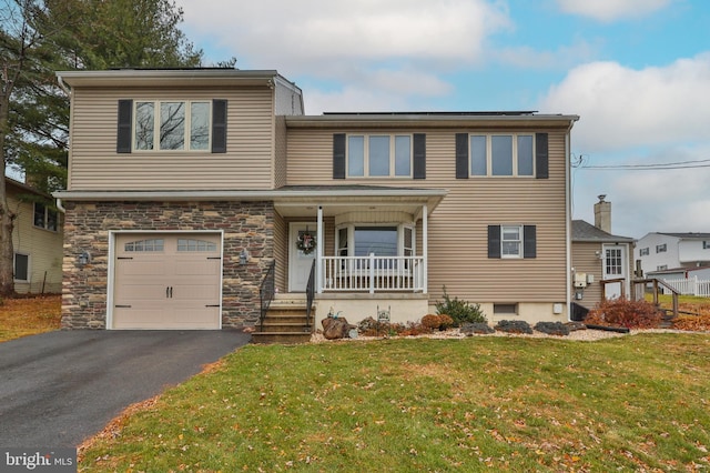 view of front of property featuring a porch, a garage, and a front lawn