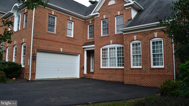 view of front of house with aphalt driveway, an attached garage, brick siding, and a shingled roof