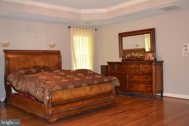 bedroom with baseboards, visible vents, a tray ceiling, dark wood-style flooring, and ornamental molding