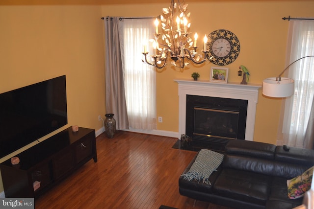 living area with a chandelier, a fireplace with flush hearth, baseboards, and wood finished floors