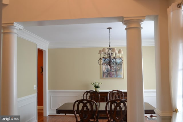 interior space with a decorative wall, a wainscoted wall, ornamental molding, decorative columns, and a notable chandelier