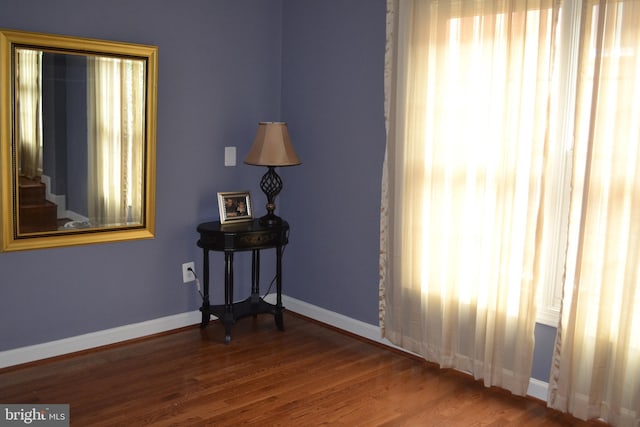 empty room with baseboards, a healthy amount of sunlight, and wood finished floors