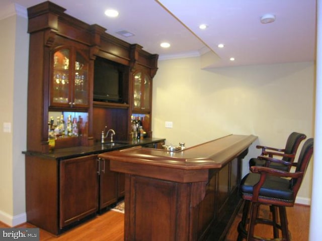 bar with ornamental molding, a sink, recessed lighting, light wood finished floors, and indoor wet bar