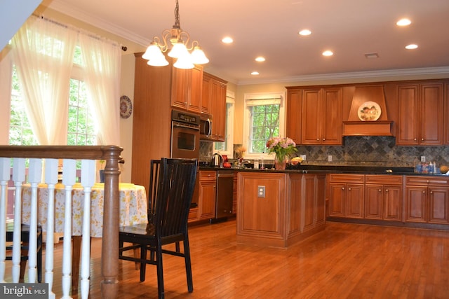 kitchen with appliances with stainless steel finishes, ornamental molding, brown cabinetry, and an inviting chandelier