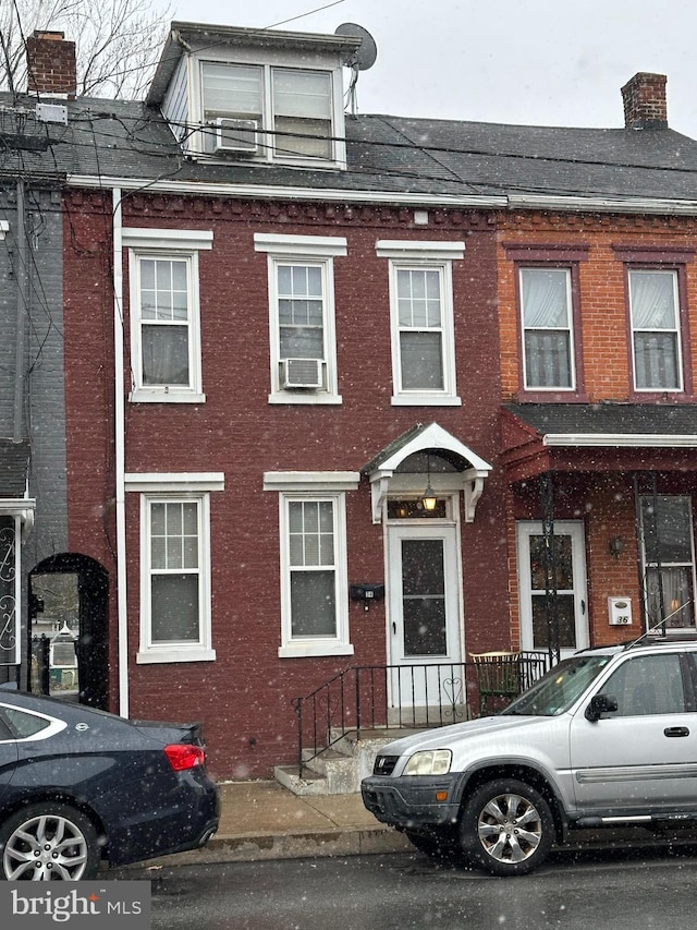 view of property with brick siding, a chimney, and cooling unit