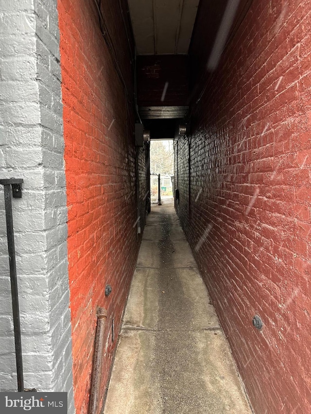 hallway with concrete flooring and brick wall