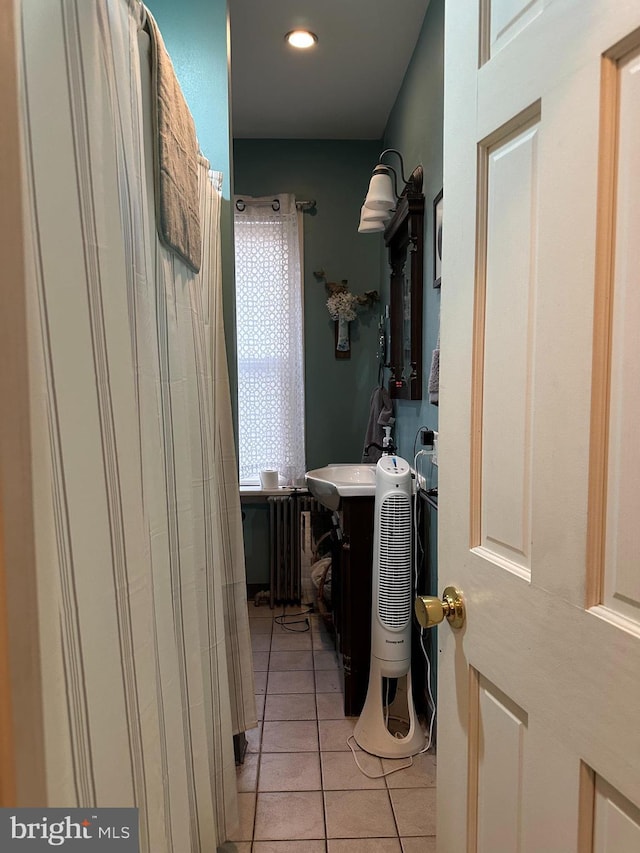 laundry area featuring light tile patterned floors, laundry area, radiator heating unit, washer and dryer, and a sink