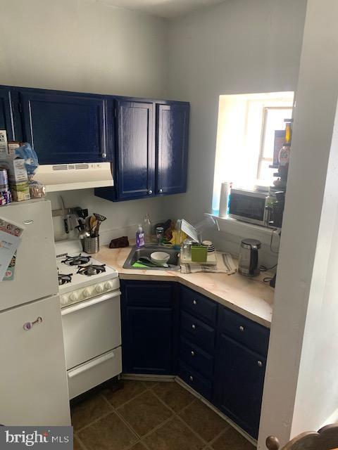 kitchen featuring extractor fan, blue cabinetry, and white appliances