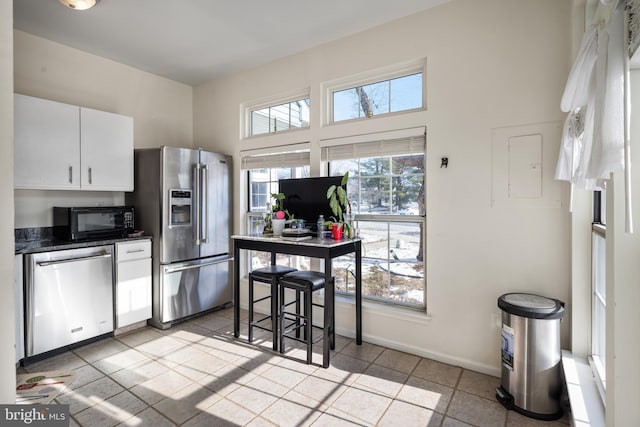 kitchen with stainless steel appliances, white cabinetry, plenty of natural light, and light tile patterned flooring