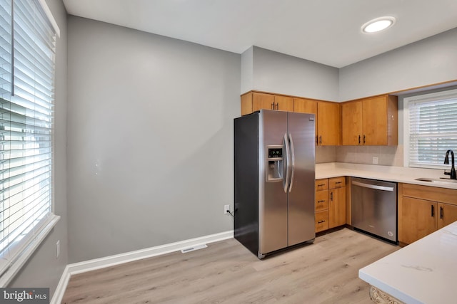 kitchen featuring appliances with stainless steel finishes, light hardwood / wood-style flooring, and sink