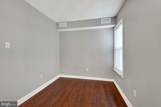 empty room with a wealth of natural light and hardwood / wood-style flooring