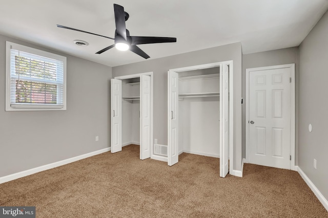 unfurnished bedroom with multiple closets, ceiling fan, and carpet