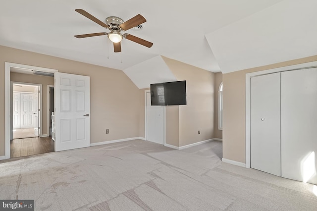 unfurnished bedroom featuring light carpet, a closet, ceiling fan, and lofted ceiling