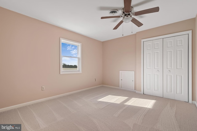 unfurnished bedroom with a closet, light colored carpet, and ceiling fan