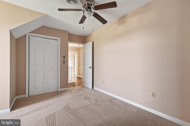 unfurnished bedroom featuring carpet, a closet, ceiling fan, and lofted ceiling