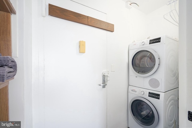 clothes washing area with stacked washing maching and dryer