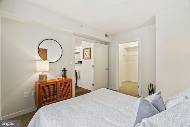 bedroom with dark colored carpet, a spacious closet, and a closet