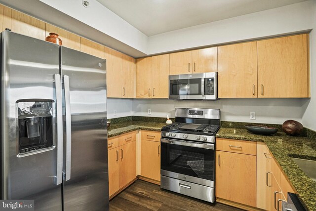 kitchen featuring light brown cabinets, stainless steel appliances, dark hardwood / wood-style floors, and dark stone countertops