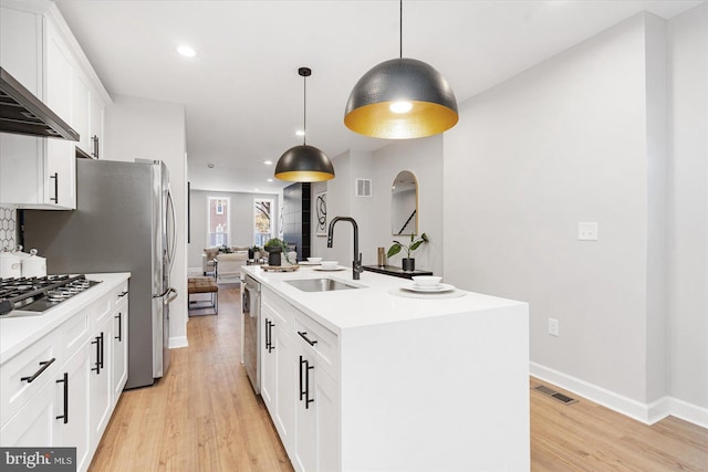 kitchen with white cabinets, sink, a kitchen island with sink, and hanging light fixtures