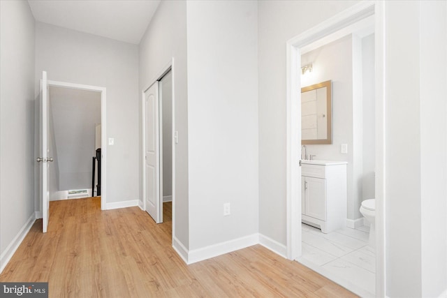 hallway with light hardwood / wood-style floors and sink