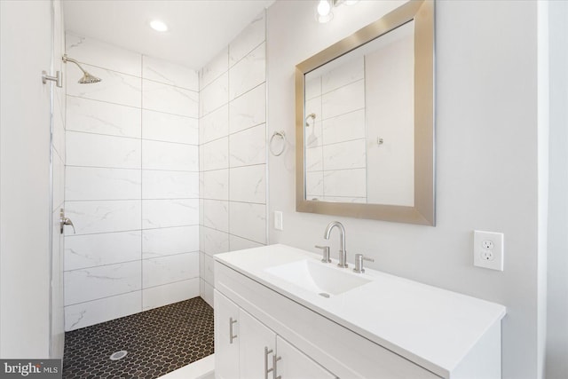 bathroom with a tile shower and vanity