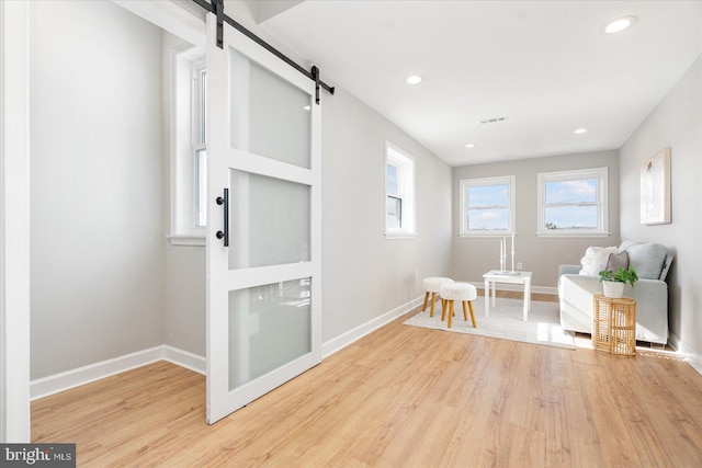 living area with a barn door and light hardwood / wood-style floors