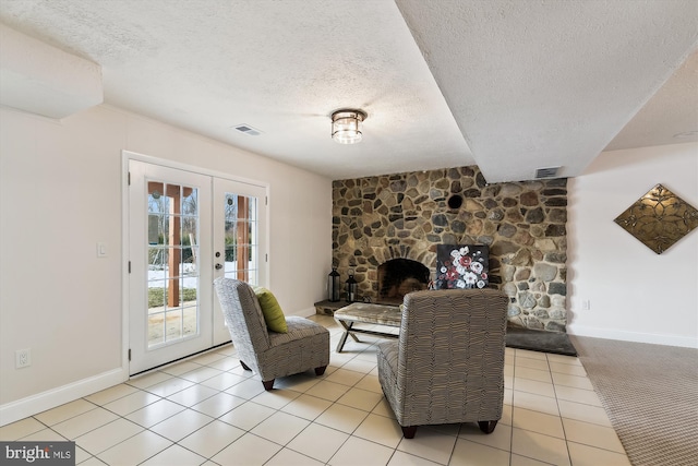 tiled living room featuring a textured ceiling, french doors, and a fireplace