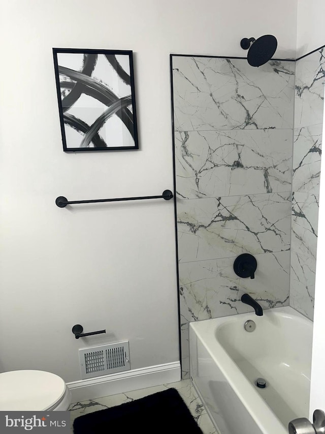 bathroom with toilet and tiled shower / bath