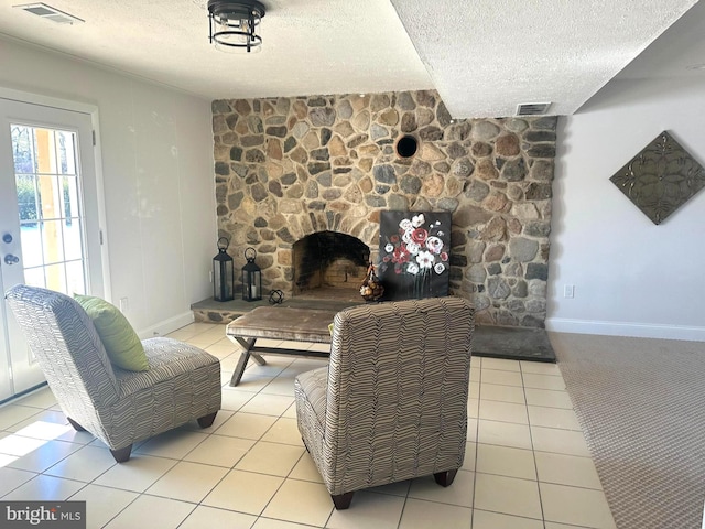 living room featuring a textured ceiling, light tile patterned floors, and a stone fireplace