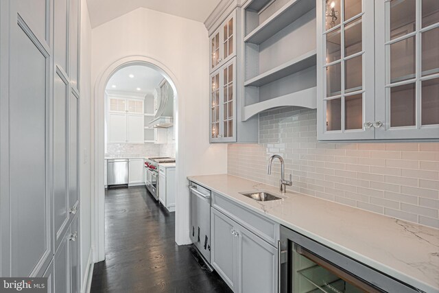 kitchen featuring sink, beverage cooler, tasteful backsplash, light stone counters, and appliances with stainless steel finishes