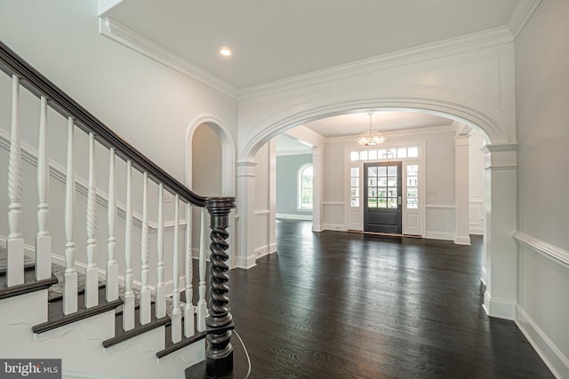 entrance foyer featuring a chandelier, crown molding, and dark wood-type flooring