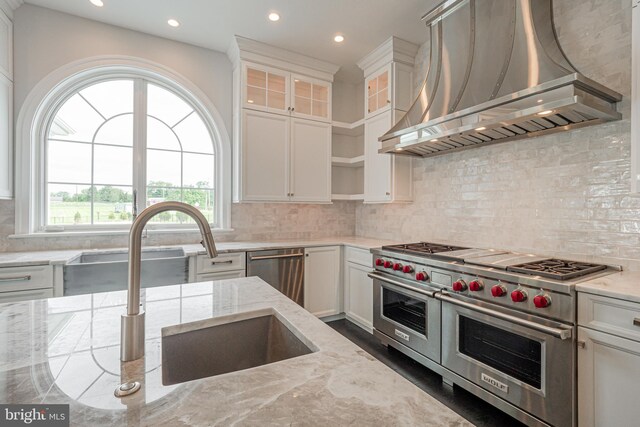 kitchen with white cabinetry, light stone countertops, wall chimney range hood, and stainless steel appliances