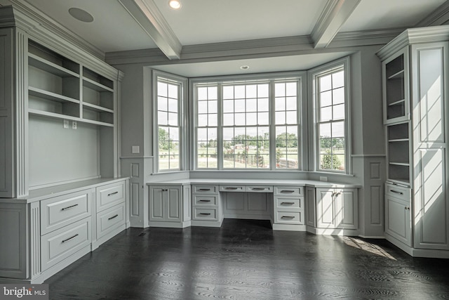 unfurnished office featuring ornamental molding, built in shelves, dark wood-type flooring, built in desk, and beamed ceiling